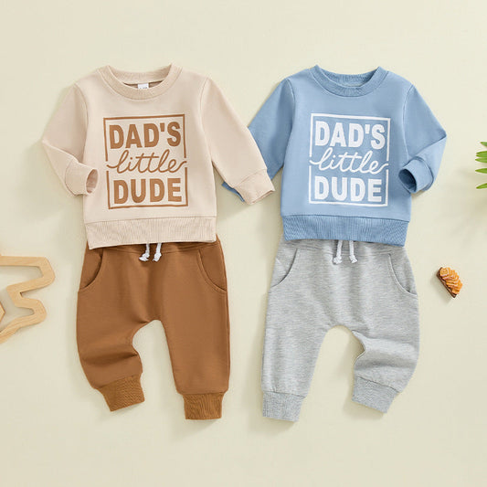 A happy baby lying on their back wearing soft Baby Joy clothing, with a parent gently performing bicycle legs to ease tummy gas in a cozy, sunlit nursery.
